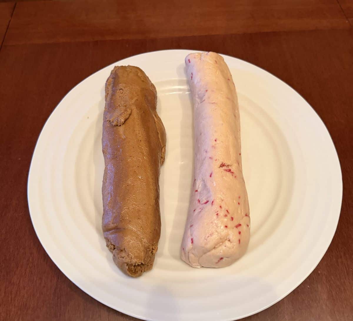 Image of two logs of cookie dough served on a white plate.