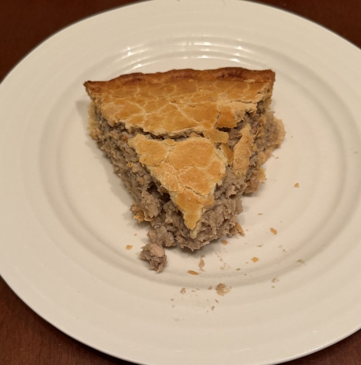 Top down image of one slice of meat pie served on a white plate.