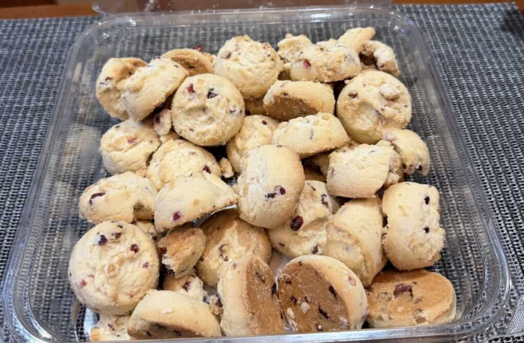 Top down image of an open container of the white chocolate cranberry shortbread cookies.