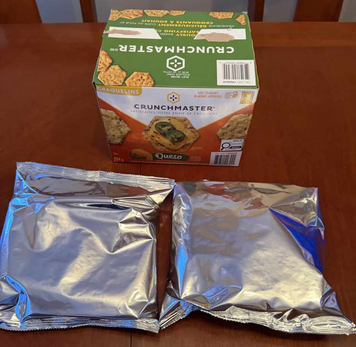 Image of two sealed bags of crackers sitting unopened in front of the box of crackers.