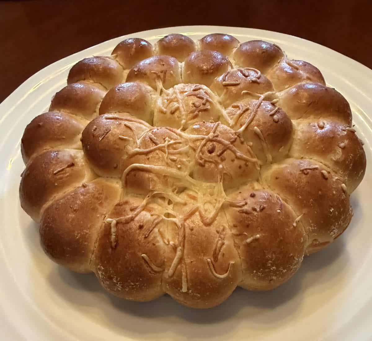 Image of the garlic & cheese pull apart brioche heated and served on a white plate.