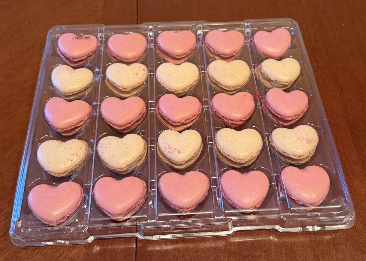 Image of a plastic tray with 25 heart-macarons in pink and white in the tray.