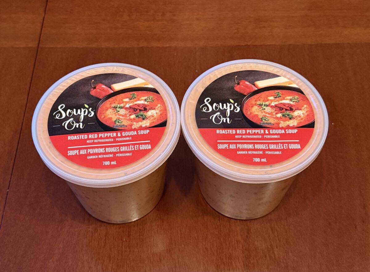 Image of two 700 milliliter containers of soup sitting on a table side by side unopened.