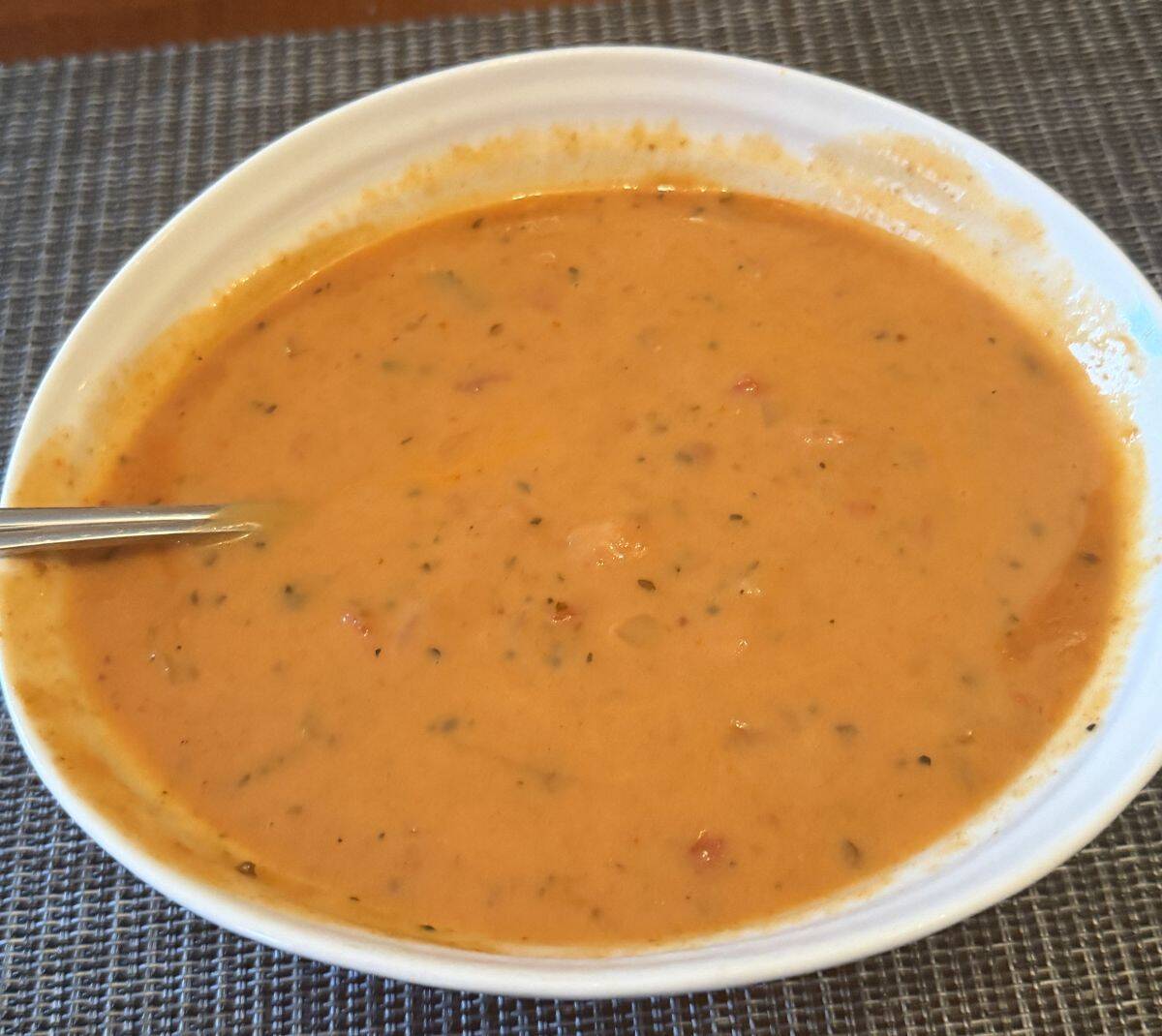 Top down image of a bowl of roasted red pepper & gouda soup.