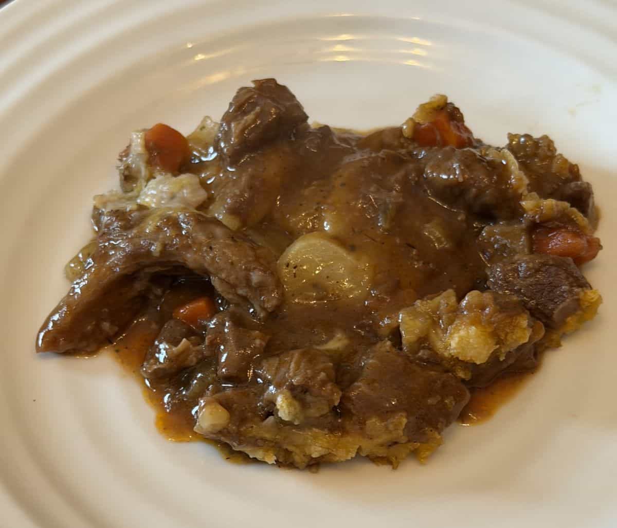 Closeup image of the steak and ale potato bake served on a white plate.