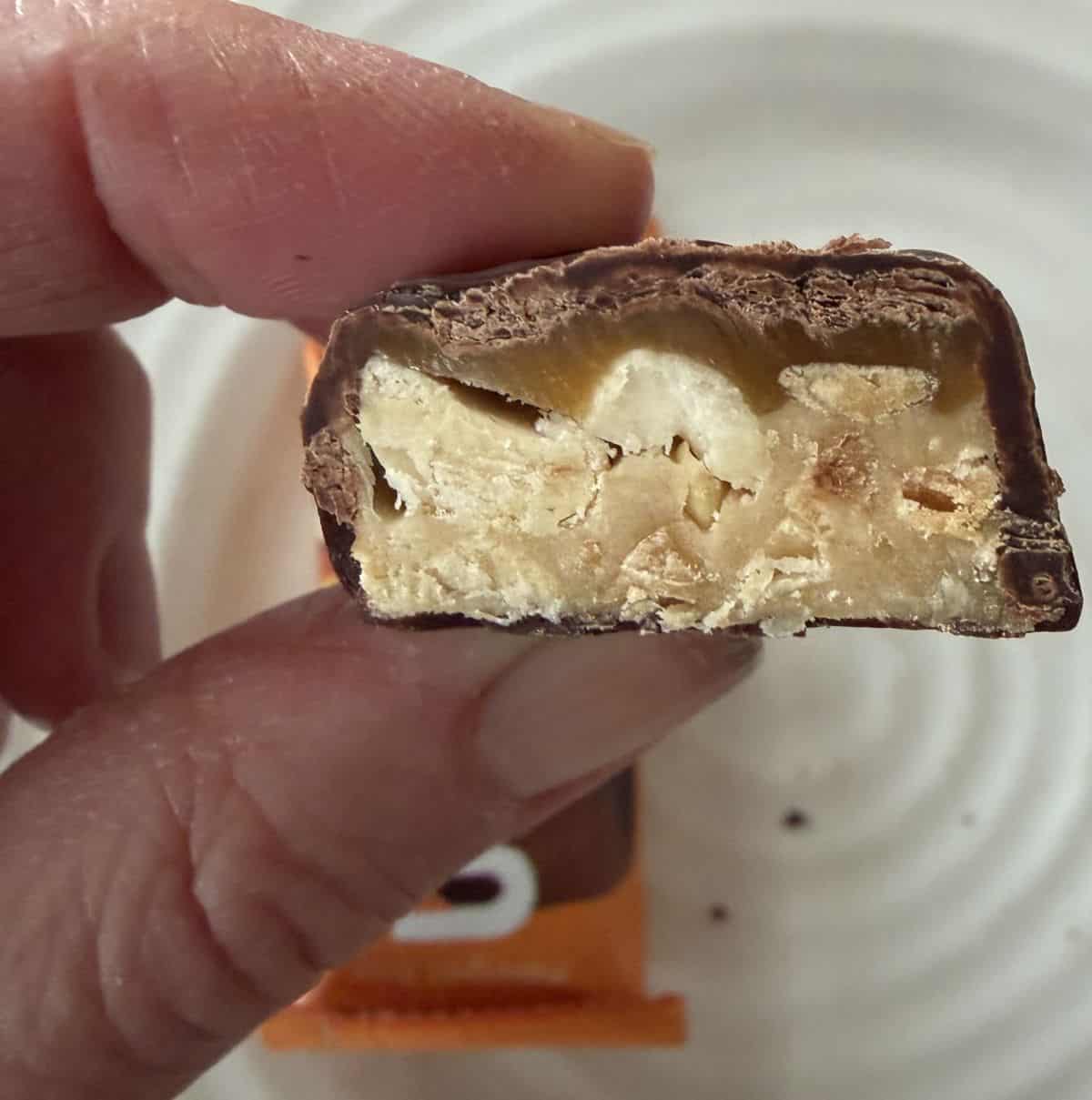 Image of a hand holding one chocolate bar close to the camera.