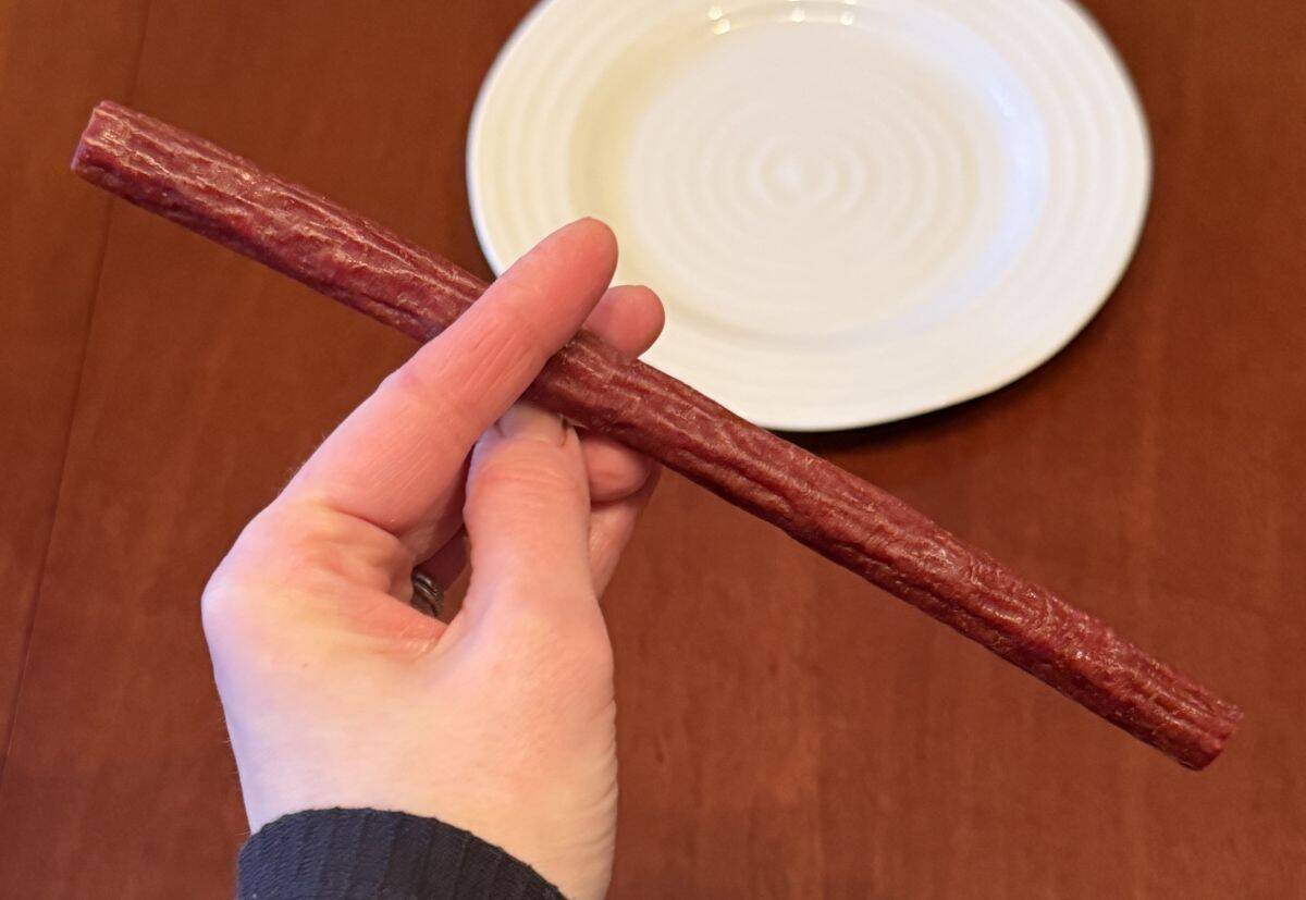 Image of a hand holding one unwrapped beef stick.