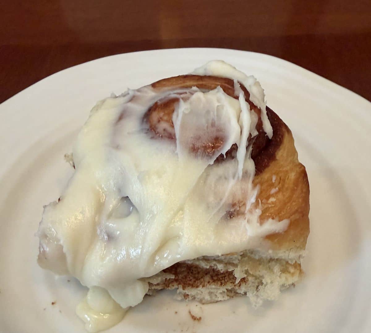 Closeup top down image of one cinnamon danish roll served on a white plate.
