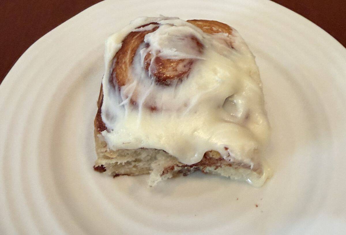 Image of one cinnamon danish roll served on a white plate.