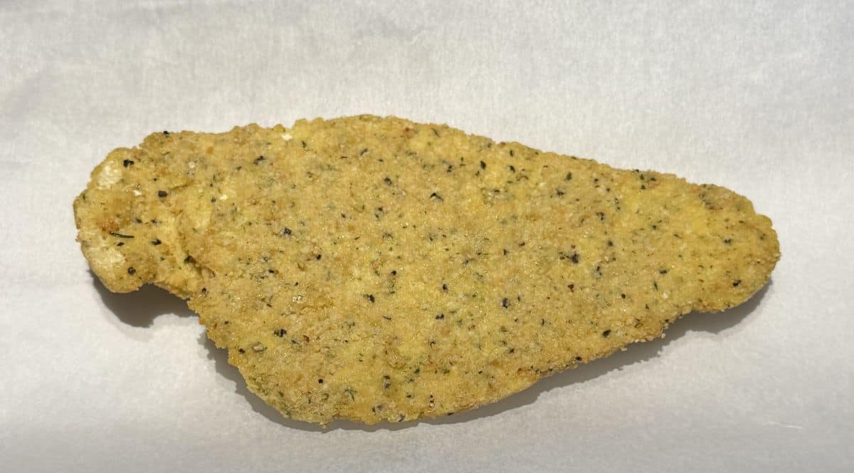 Image of one frozen sole fillet on a parchment paper lined baking tray before baking it.