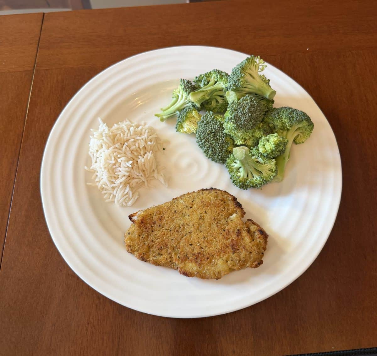 Image of a white plate with rice,cooked lemon pepper sole and broccoli on it.