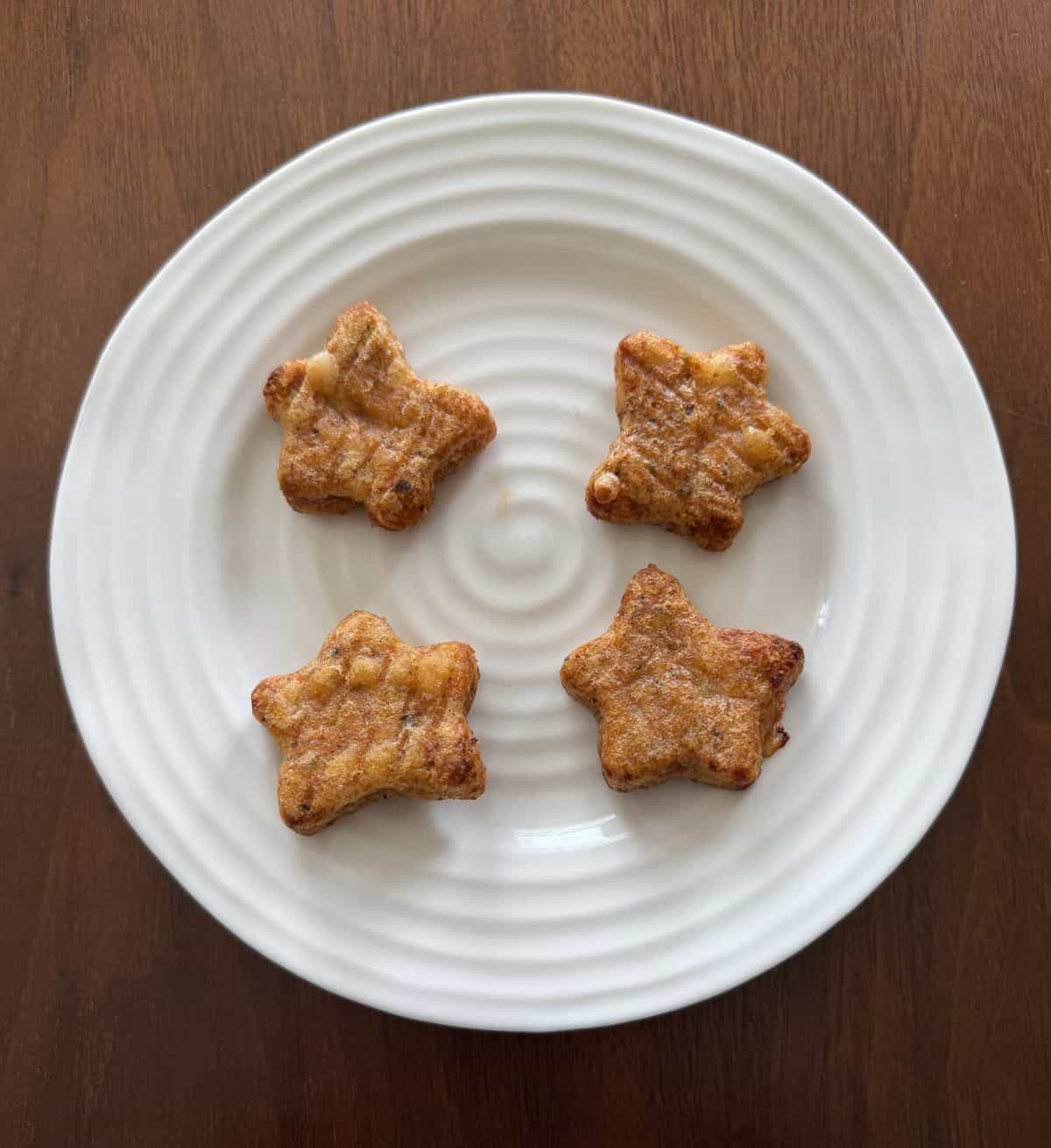 Top down image of four heated pizza stars on a white plate.