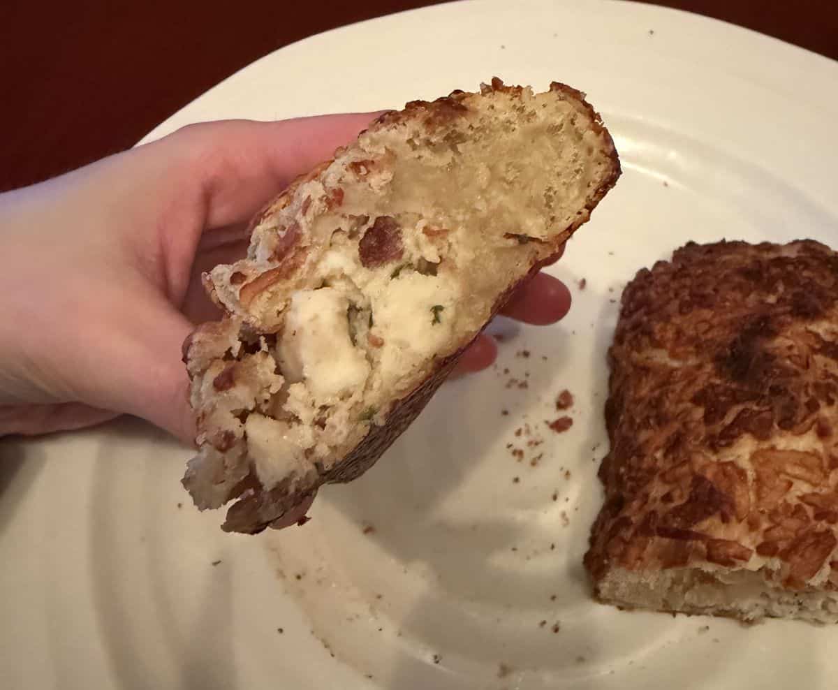 Image of hand holding one chicken bake that's been cut in half so you can see the filling.