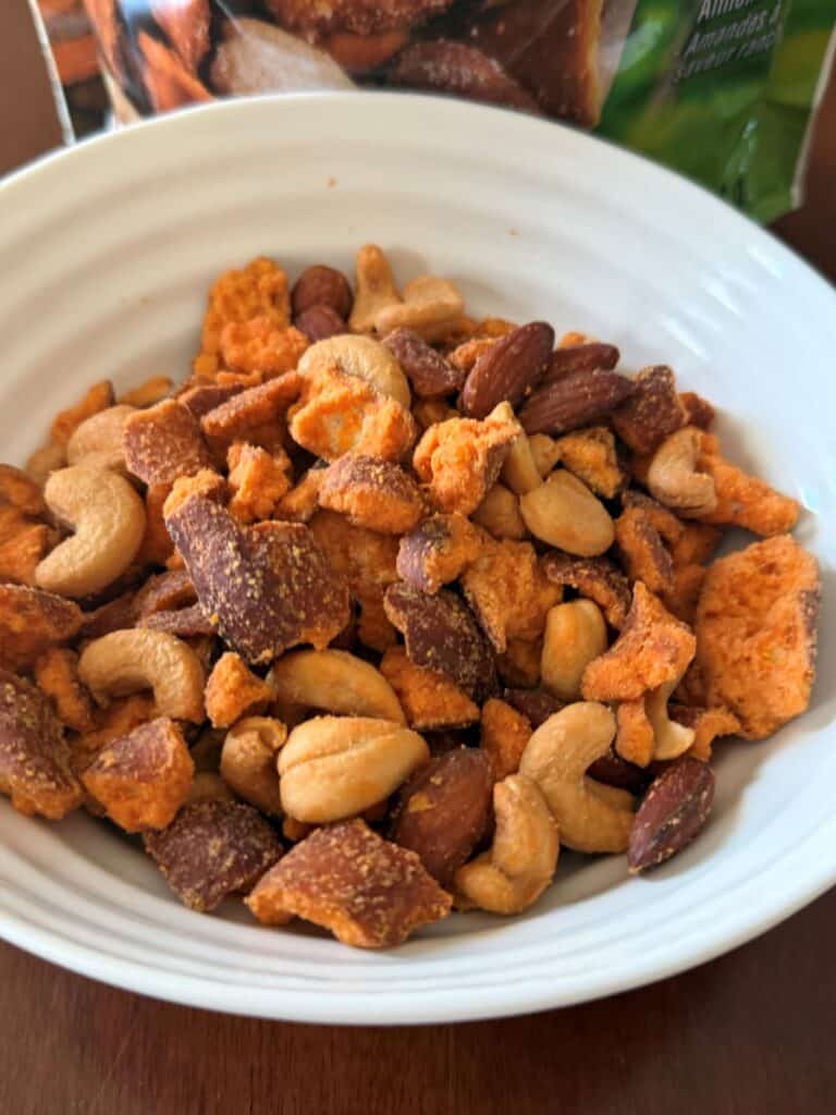 Closeup top-down image of the pretzel nut mix served in a white bowl.