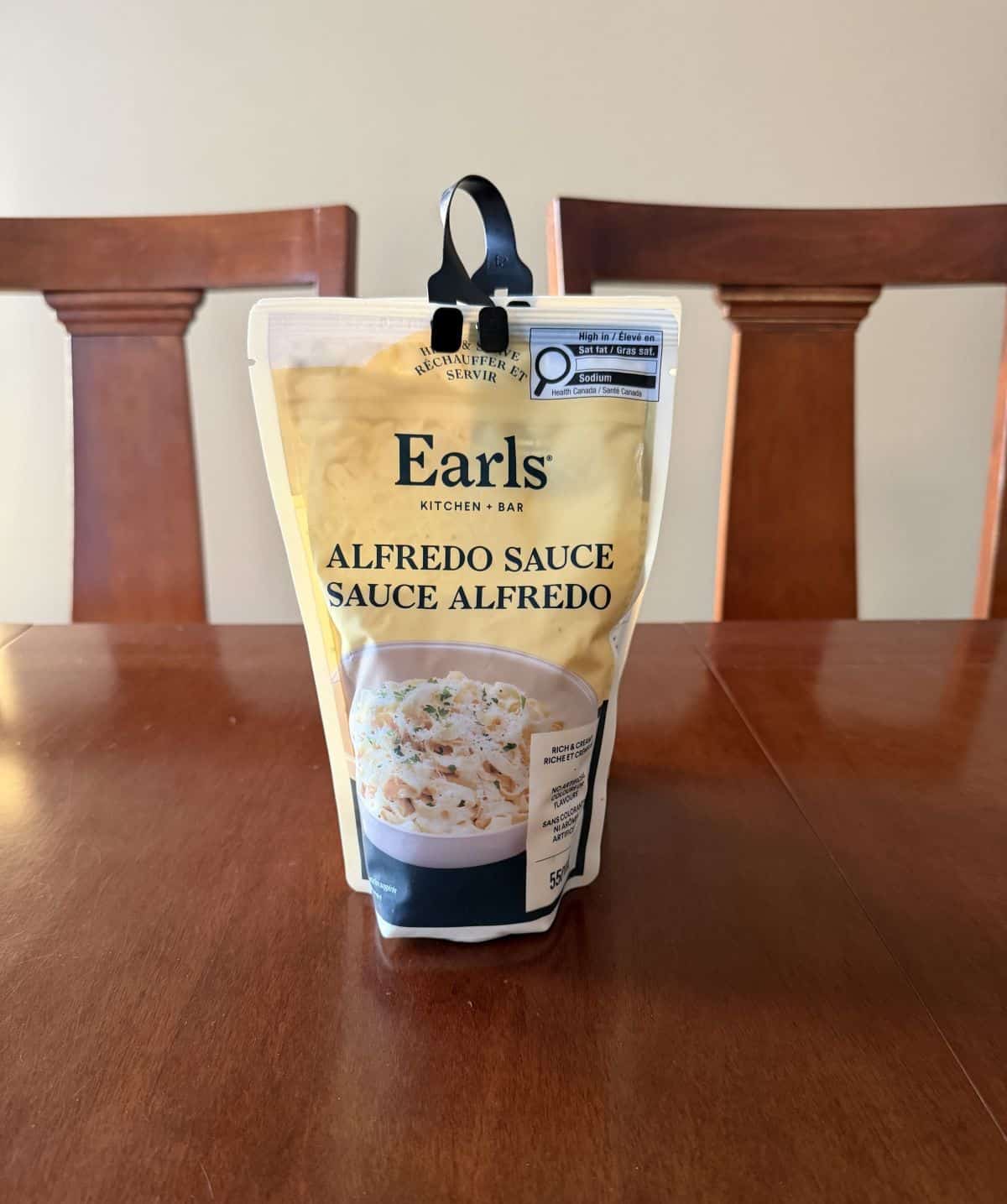Image of the Costco Earls Alfredo Sauce sitting on a table unopened. 
