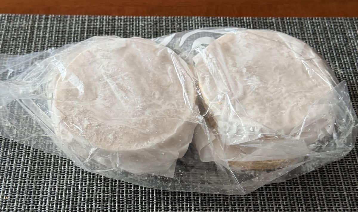 Image of frozen chicken burgers packaged in plastic and sitting on a table unopened.