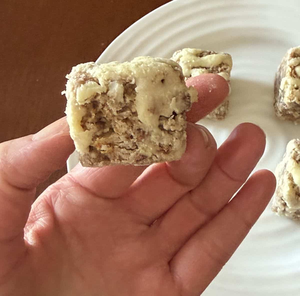 Image of a hand holding one carrot cake heavenly hunk close to the camera.