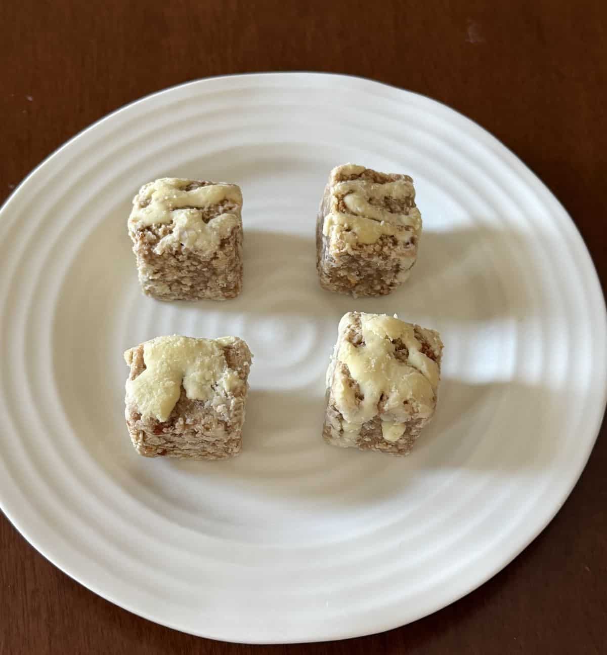 Image of four heavenly hunks carrot cake bites served on a white plate.