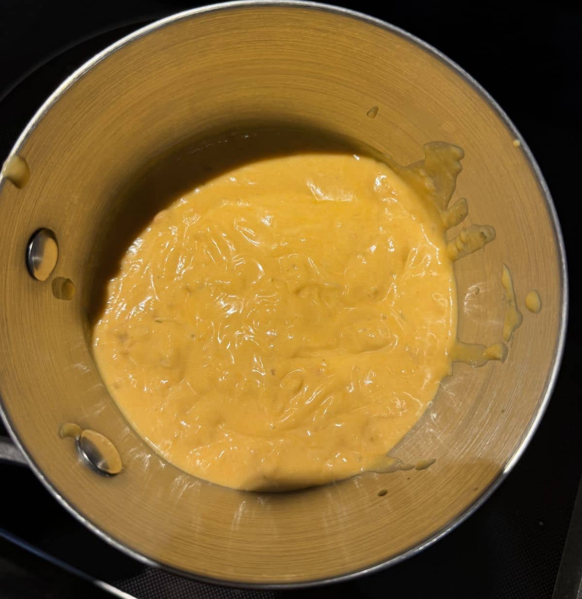 Top down image of the lobster sauce being heated in a saucepan.