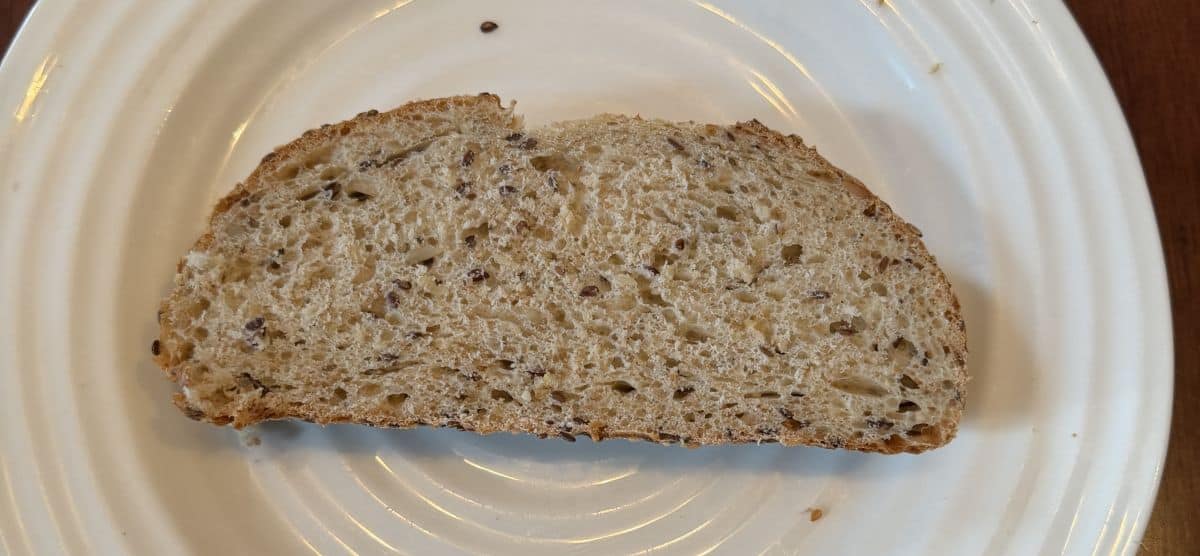 Image of one slice of Wholesome Grains Sourdough served on a white plate.