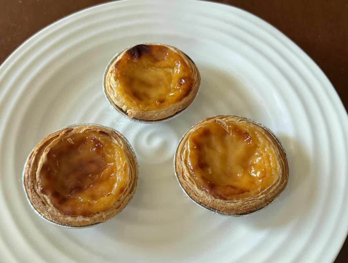Image of three Portuguese custard tarts served on a white plate.