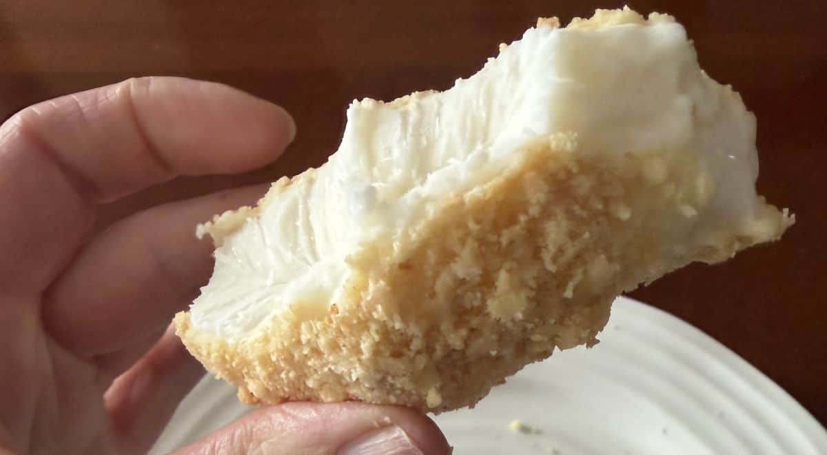 Image of a hand holding one drumstick close to the camera that's been about half eaten so you can see the filling and cookie outside.