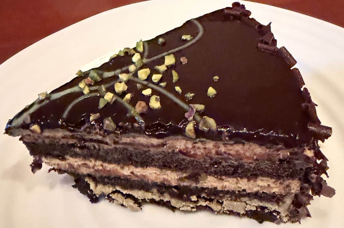 Top down image of one slice of Pistachio Chocolate Cake served on a white plate.