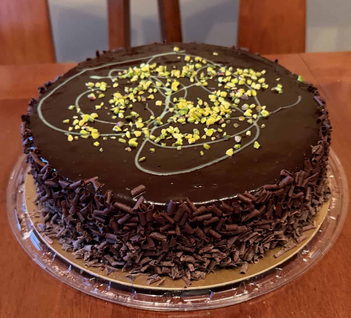 Sideview image of the Pistachio Chocolate Cake before slicing it, sitting on a table.