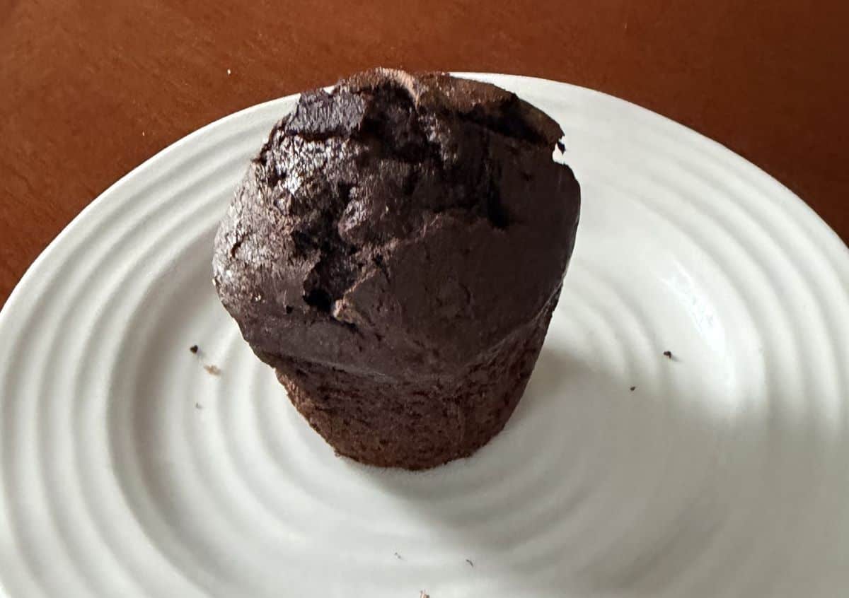 Image of one chocolate muffin served on a white plate.