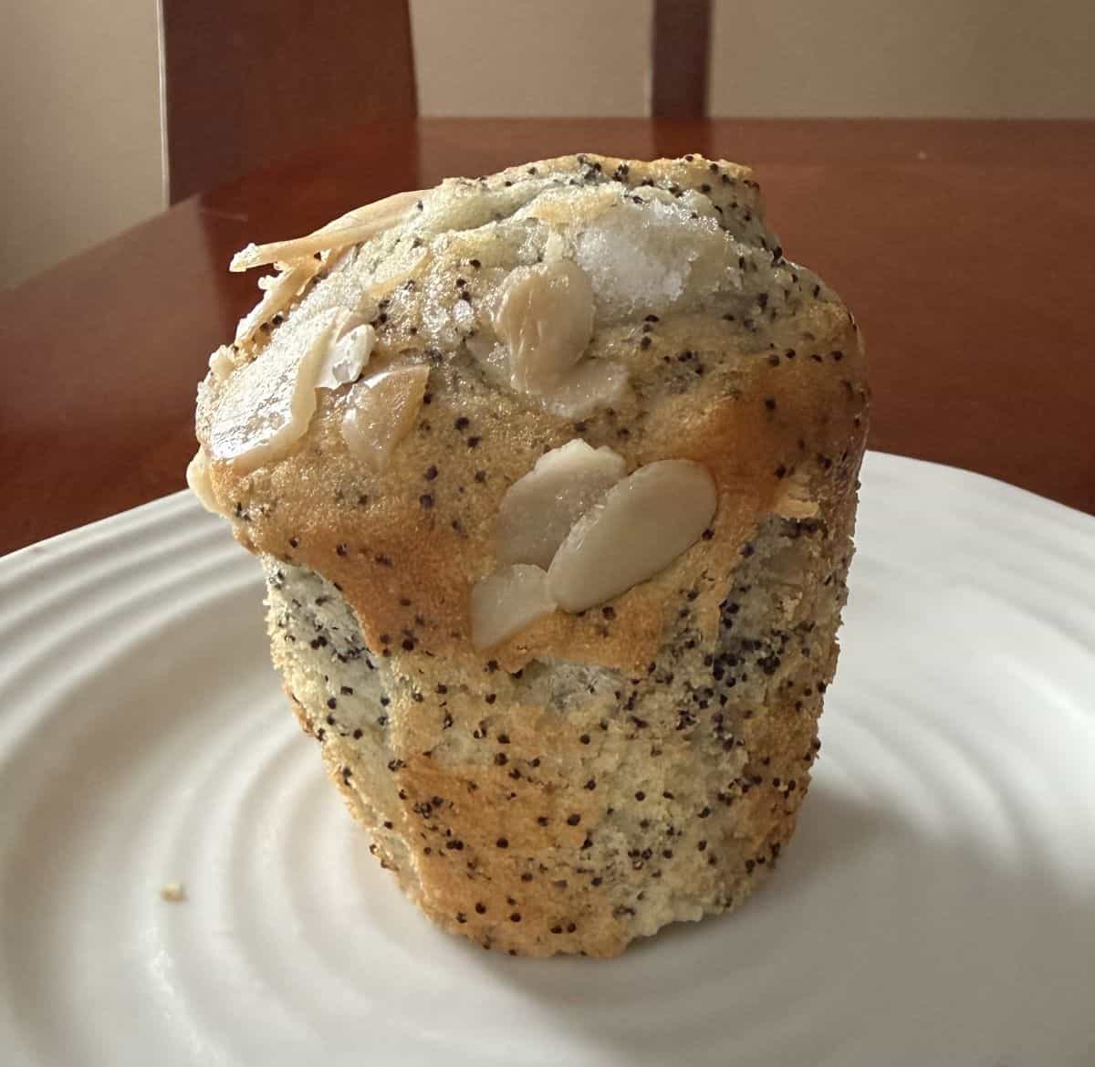 Image of one almond poppy seed muffin served on a white plate.