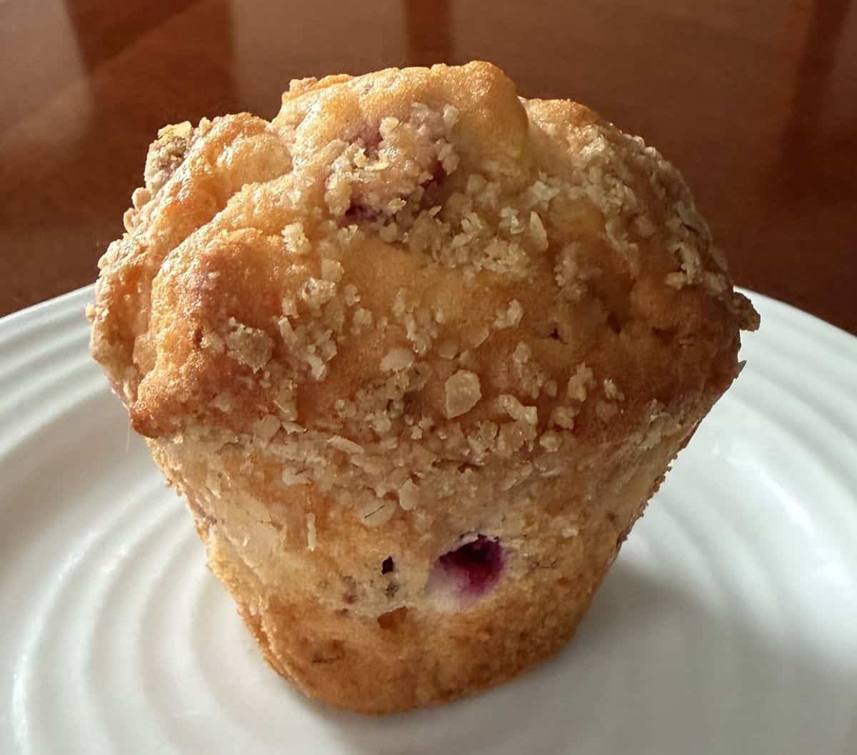 Image of one cranberry orange muffin served on a white plate.