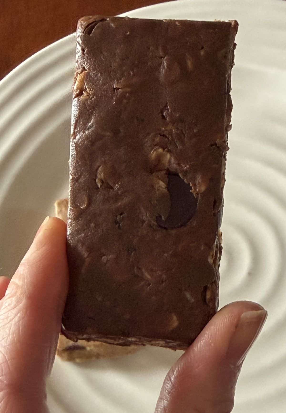 Closeup image of a hand holding one double chocolate Mush bar close to the camera.
