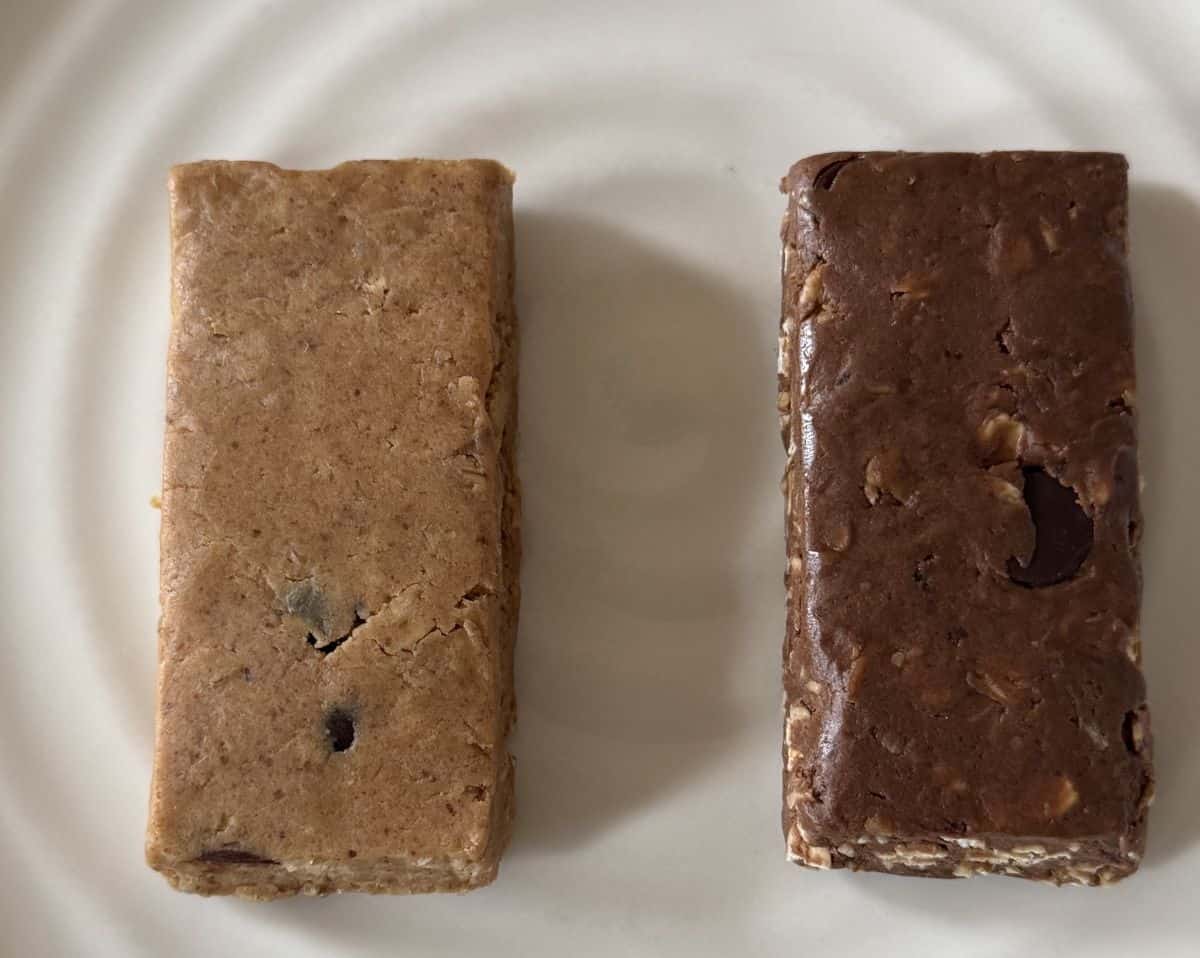 Closeup image of one peanut butter and one double chocolate Mush bar beside one another unwrapped on a white plate.