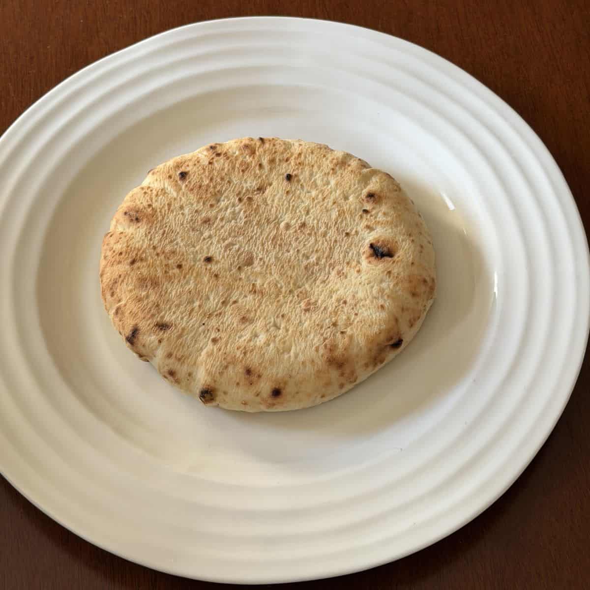 Image of one pita bread piece served on a white plate.