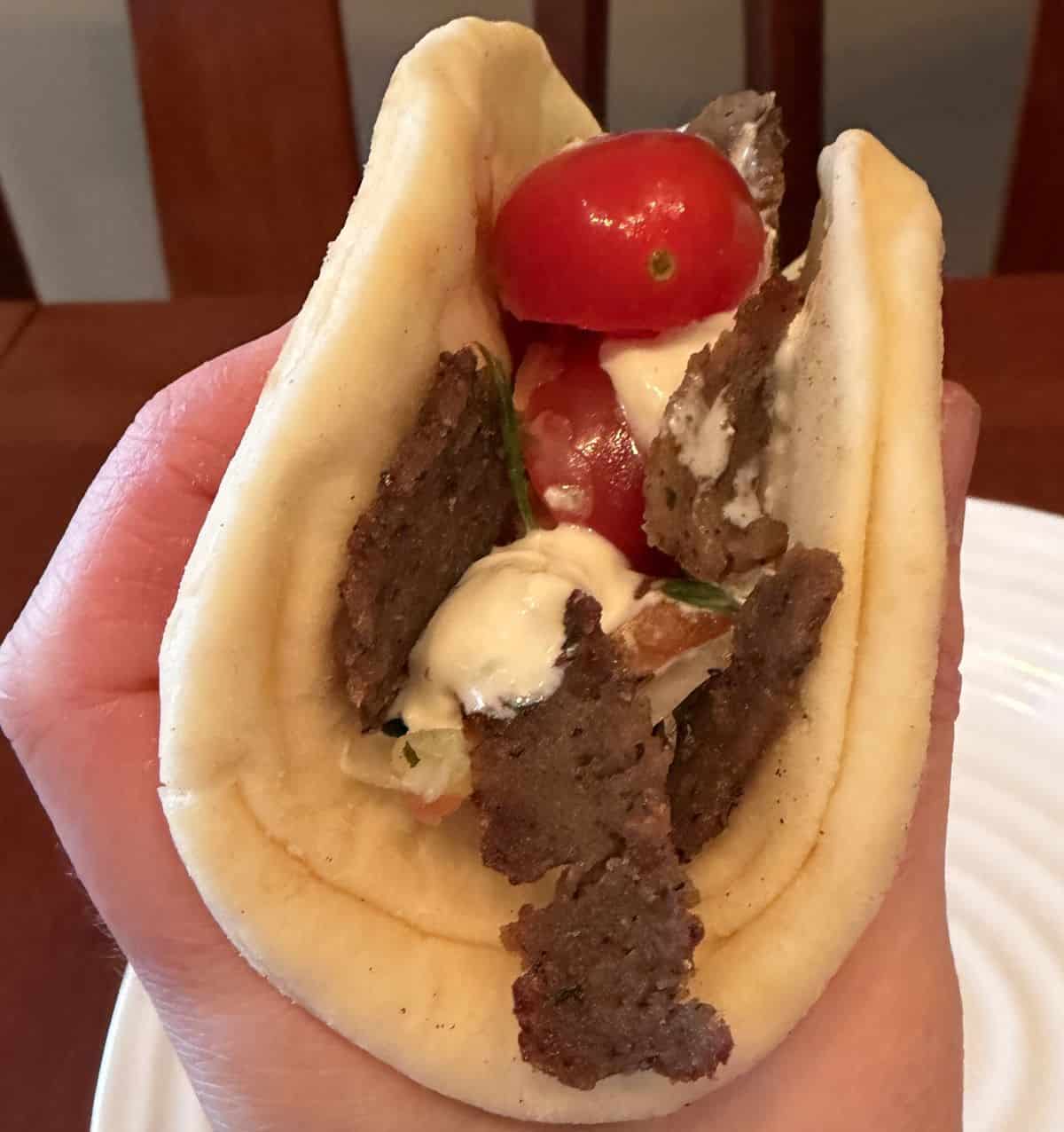 Image of a hand holding one gyro pita close to the camera.