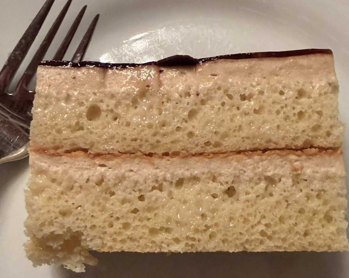 Closeup top down image of a slice of cake served on a white plate.