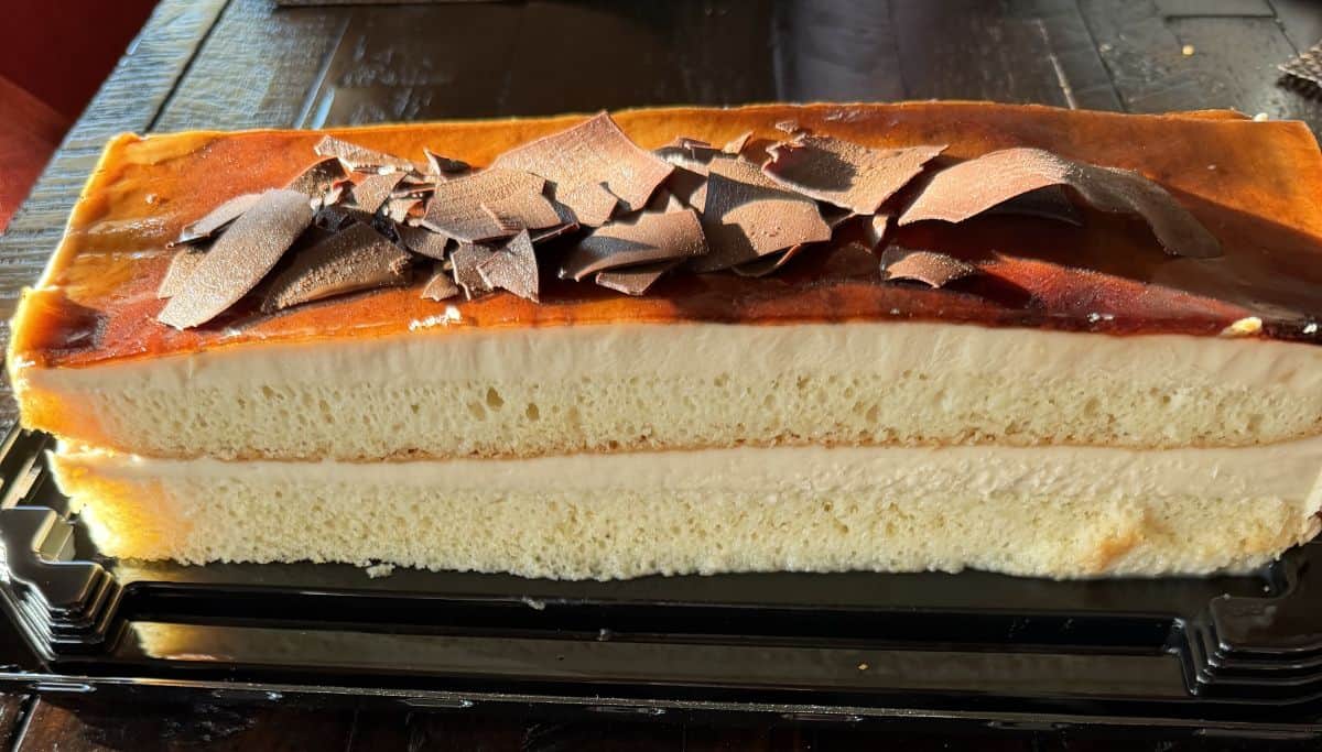 Closeup sideview image of the entire cake with the lid off on a table so you can see all the layers of the cake.