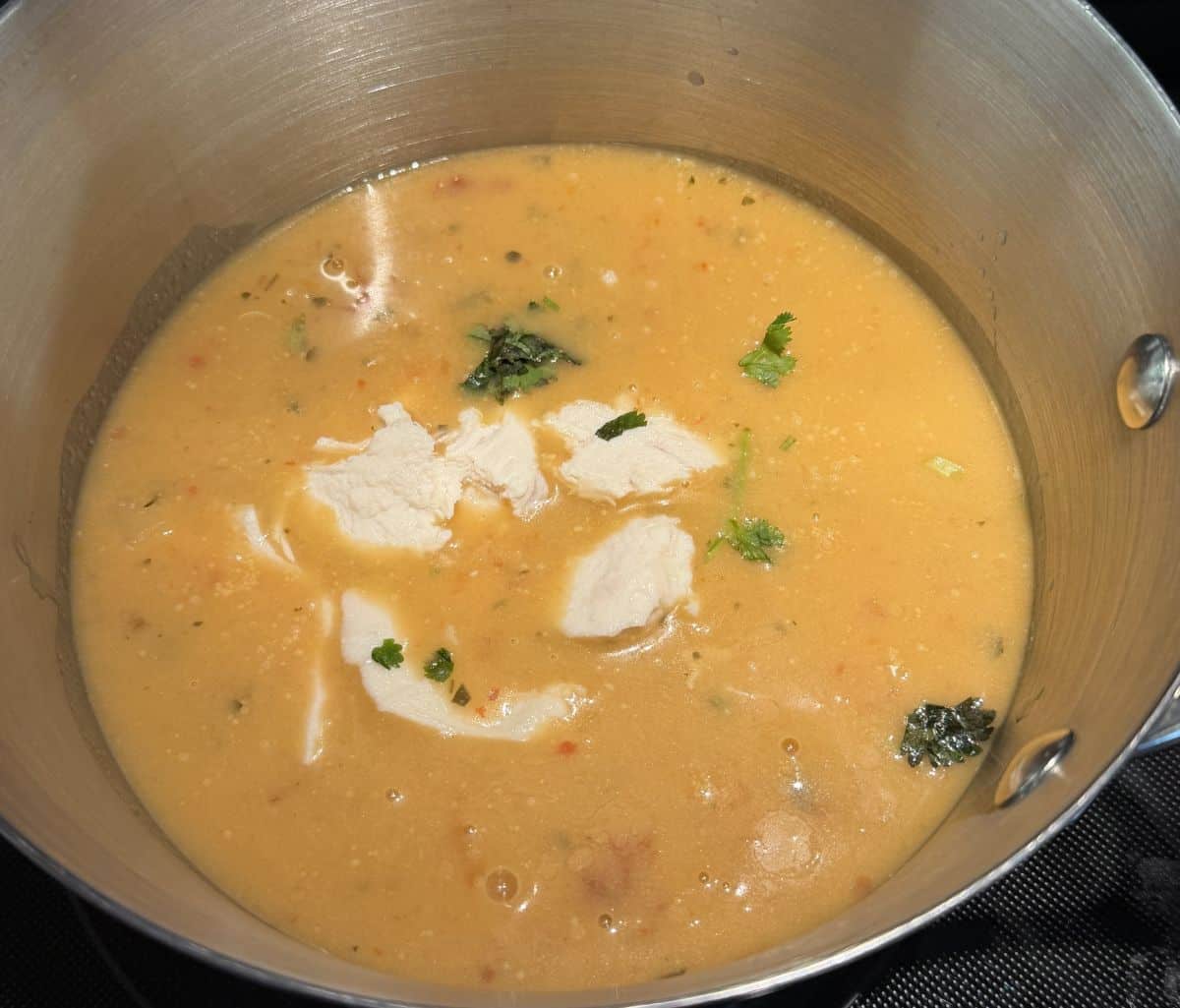 Image of the Tom Yum Soup broth and chicken simmering in a pot on the stove.