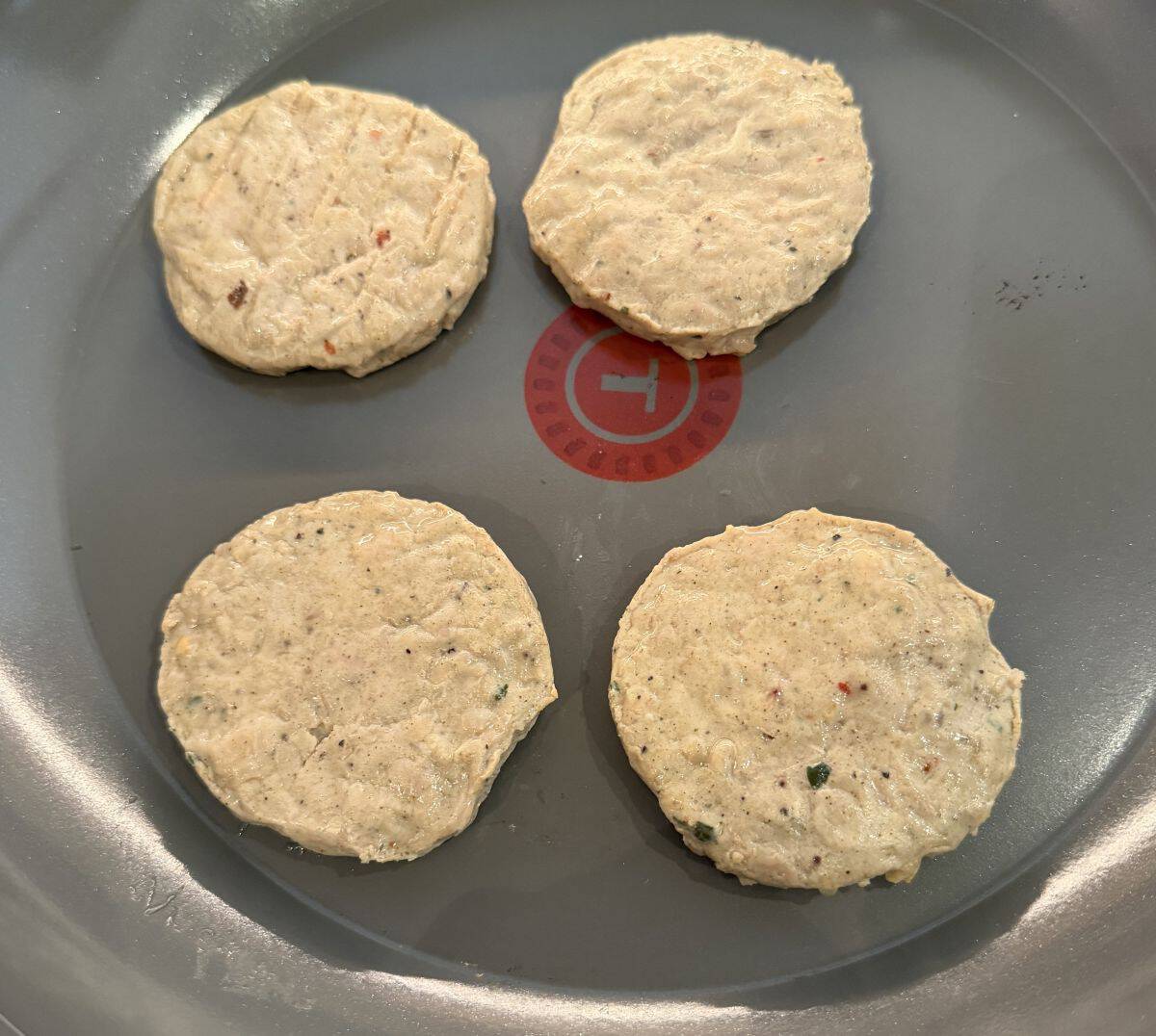 Image of the chicken patties being heated in a frying pan on the stove.