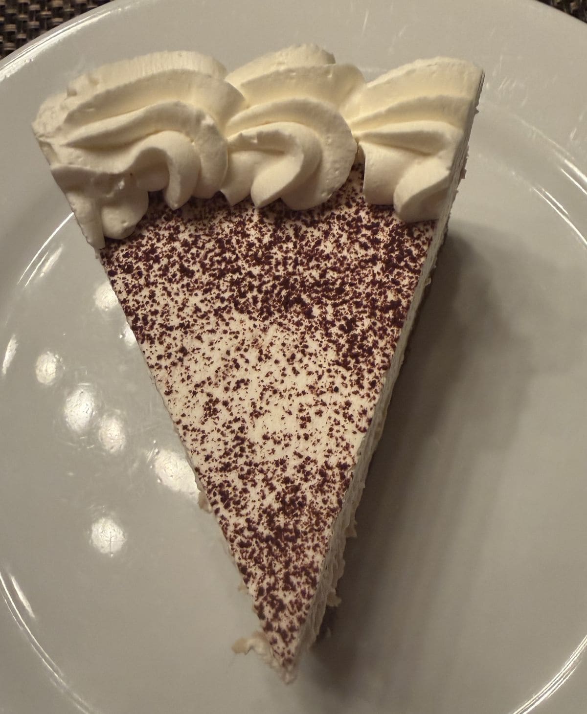 Top down image of one slice of cheesecake served on a white plate.