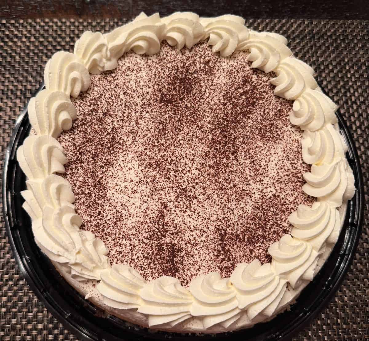 Top down image of the entire cheesecake served on a table without the lid on.