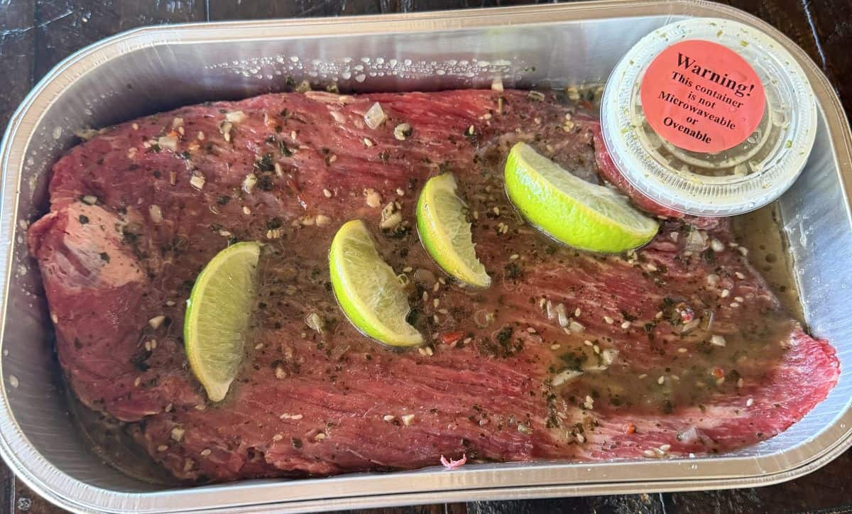 Image of the Kirkland Signature Flank Steak with Cilantro Lime Marinade tray sitting on a table opened so you can see what it looks like raw.