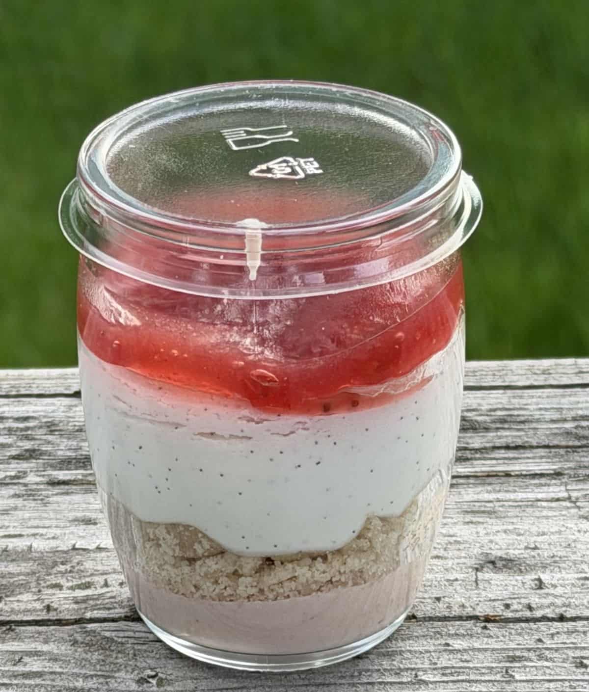 Closeup image of one unopened individual strawberry shortcake sitting on a deck outside.