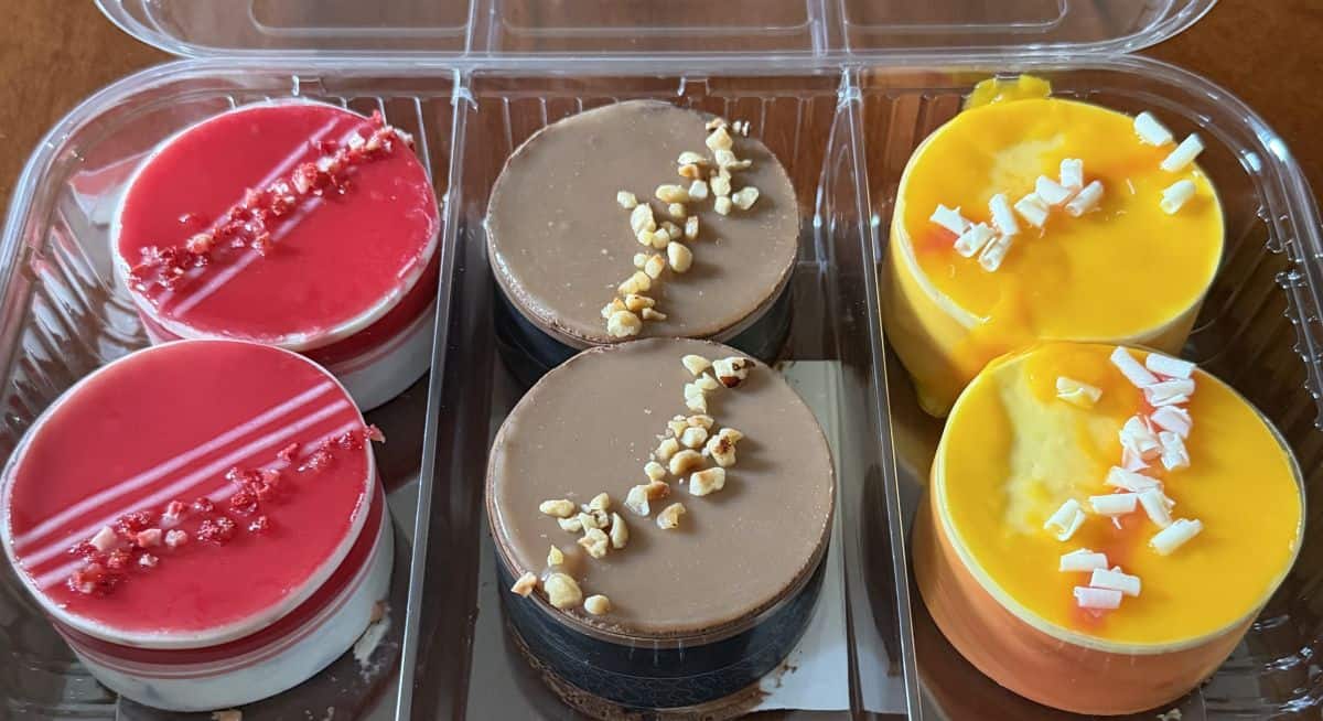 Top down image of a pack of six mousse cakes in a plastic package, there are two of each flavor.