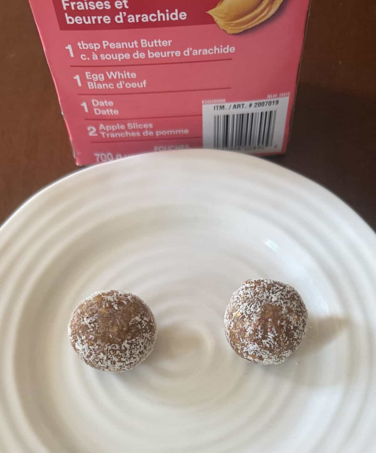 Image of two energy bites served on a white plate in front of the box of RX Energy Bites.