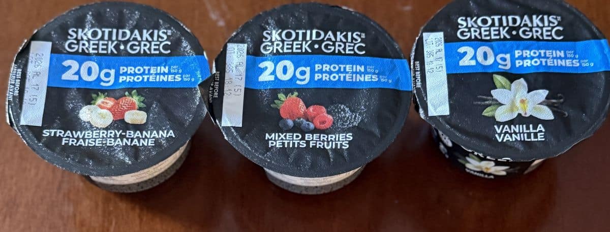Image of the three flavors of Protein Greek Yogurt served on a table unopened.