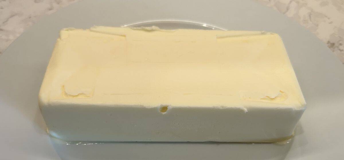Image of one block of butter unwrapped and sitting on a butter dish.