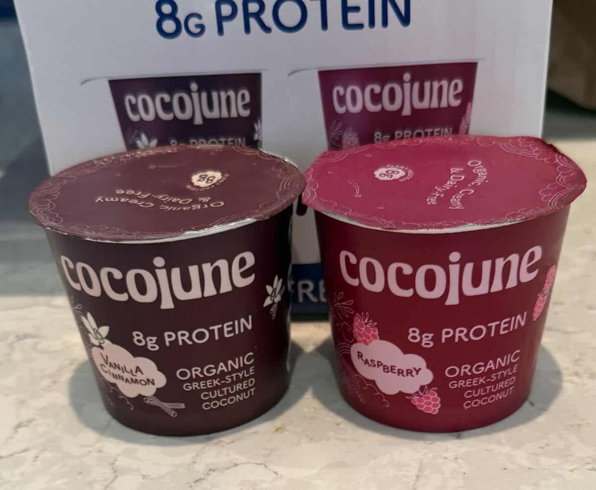 Image of one raspberry and one vanilla cinnamon yogurt sitting beside each other on a counter in front of the yogurt box.