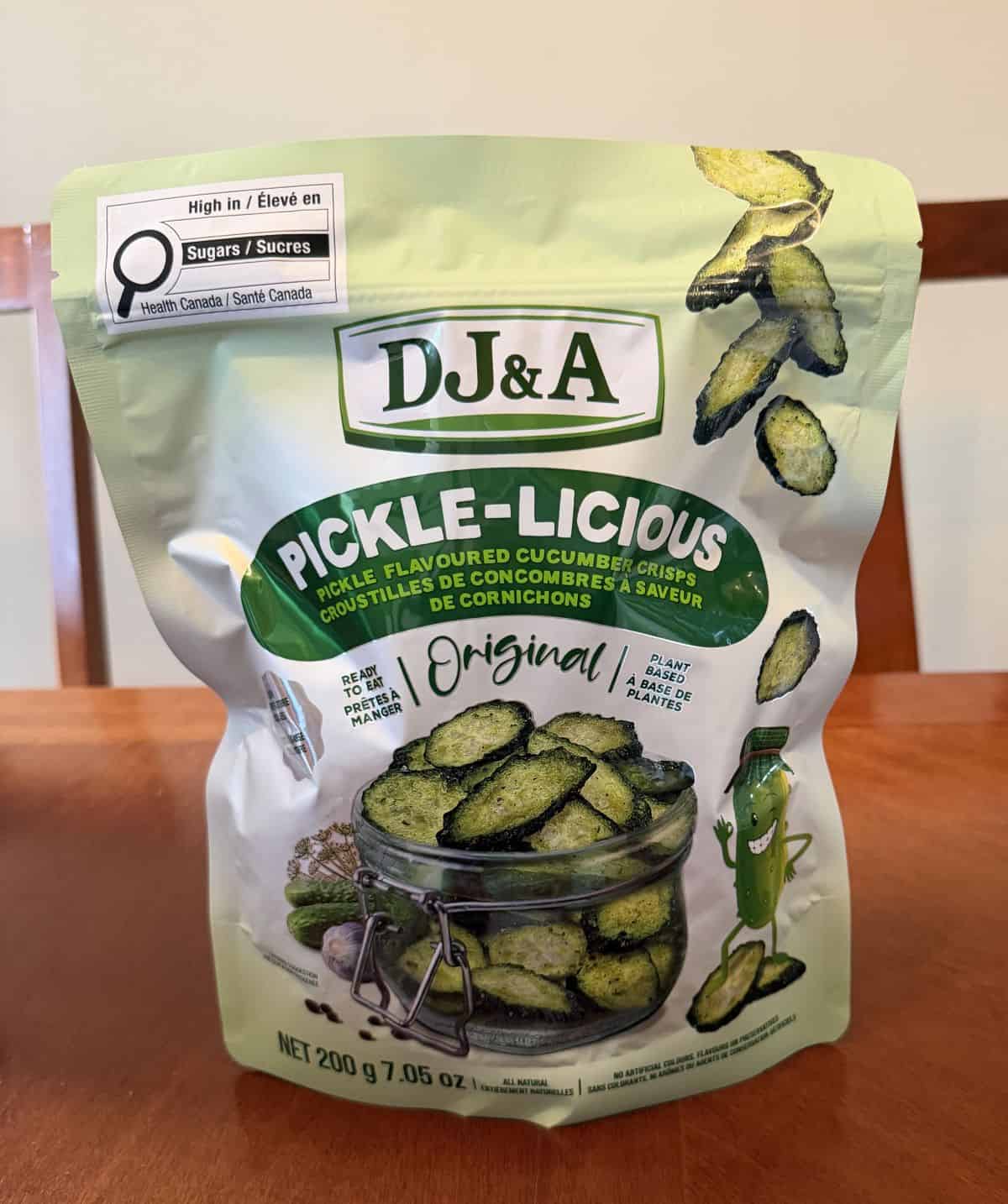 Image of the Costco DJ&A Pickle-Licious Pickle Flavored Cucumber Crisps bag sitting on a table unopened.