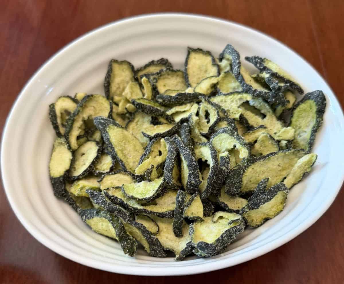 Top down image of the cucumber crisps served in a white bowl.